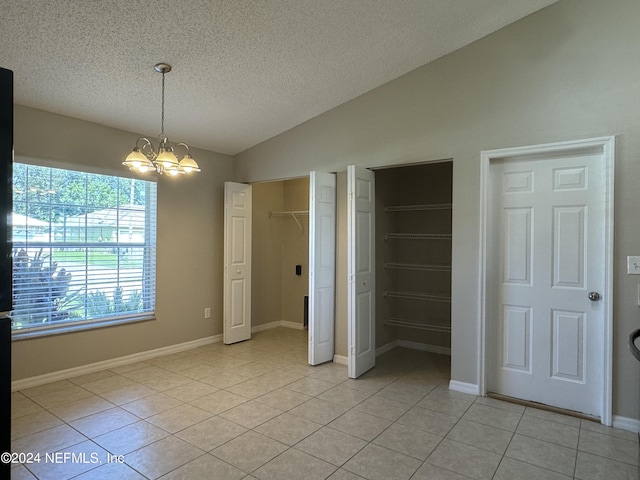 unfurnished bedroom featuring light tile patterned flooring, multiple closets, a notable chandelier, and vaulted ceiling