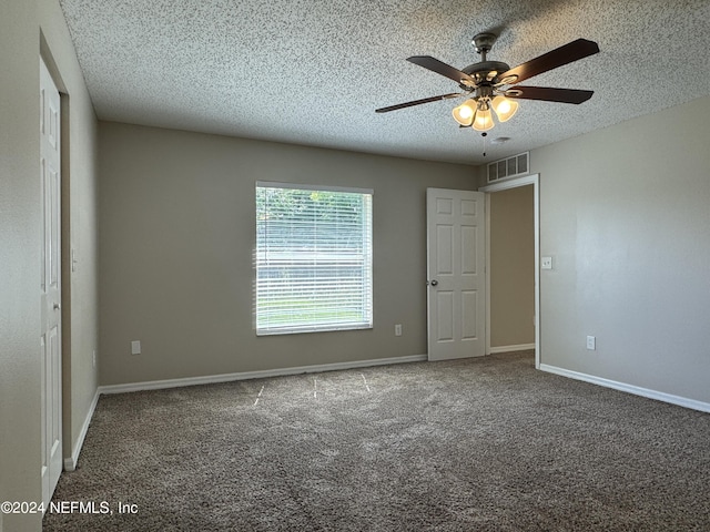 unfurnished bedroom featuring a textured ceiling, visible vents, baseboards, a ceiling fan, and carpet floors