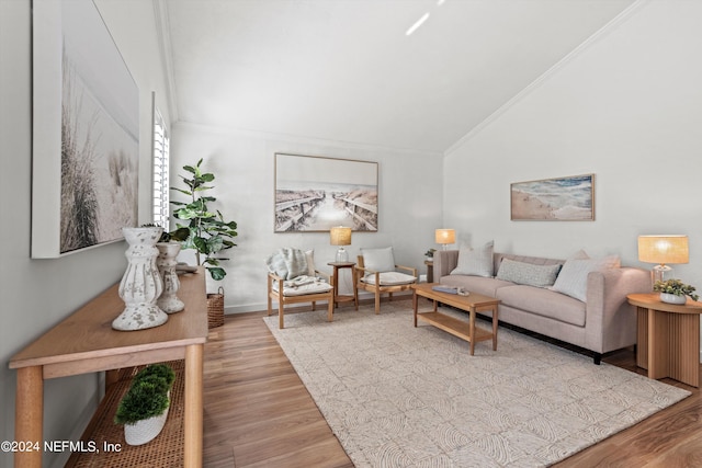 living room with ornamental molding, light wood-type flooring, and vaulted ceiling