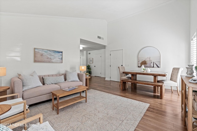 living room featuring high vaulted ceiling, light hardwood / wood-style floors, and ornamental molding