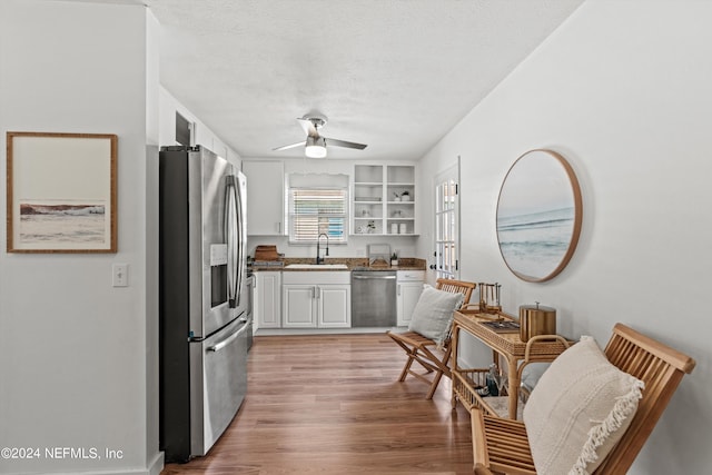 kitchen featuring light hardwood / wood-style floors, white cabinetry, stainless steel appliances, a textured ceiling, and ceiling fan