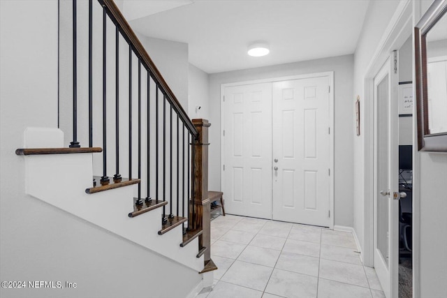 entryway featuring light tile patterned flooring, baseboards, and stairway