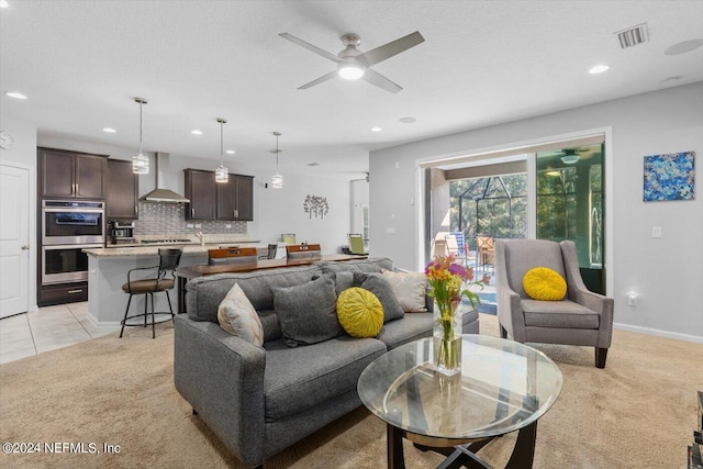 living room with ceiling fan, light colored carpet, and a textured ceiling