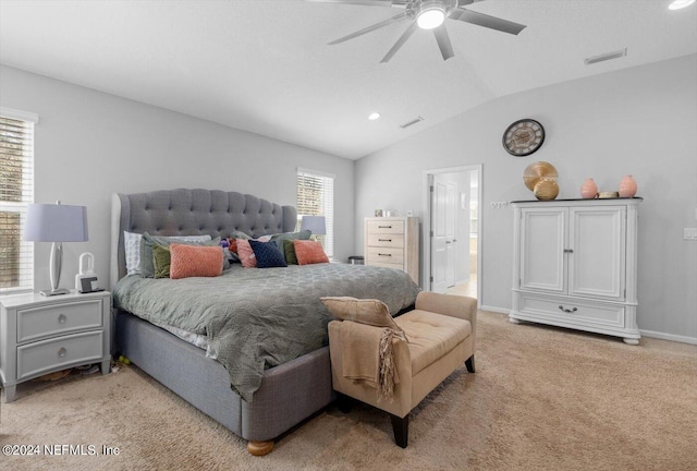 bedroom with light carpet, connected bathroom, vaulted ceiling, and ceiling fan