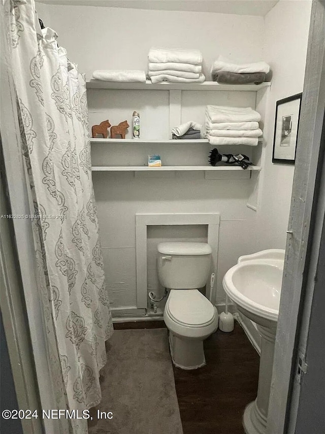 bathroom with a shower with shower curtain, hardwood / wood-style floors, and toilet