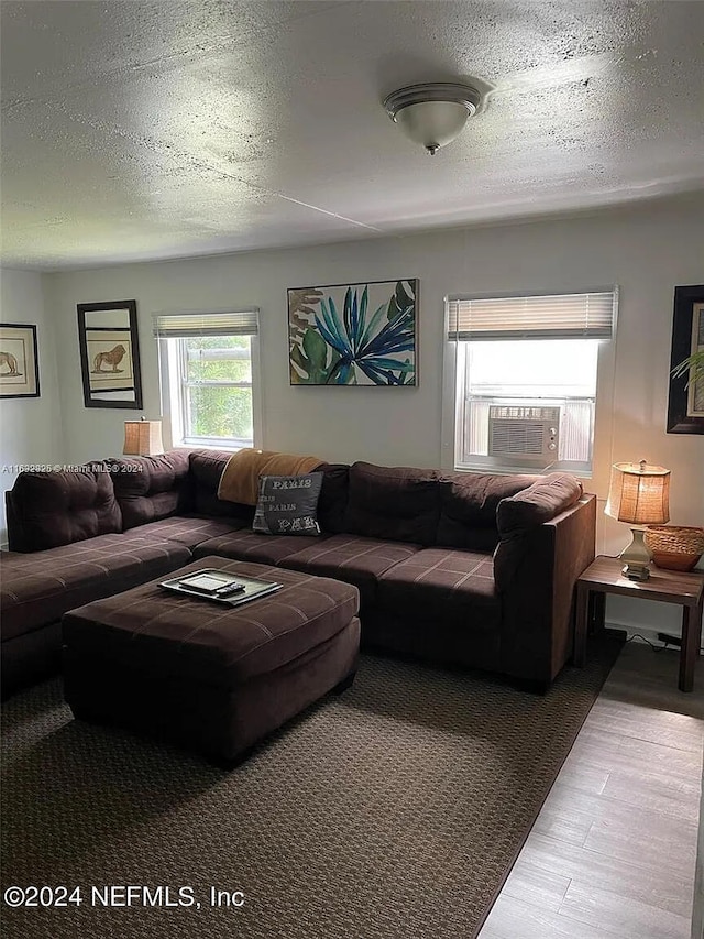 living room with cooling unit, light hardwood / wood-style floors, and a textured ceiling