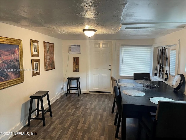 dining space featuring a textured ceiling, an AC wall unit, and dark wood-type flooring