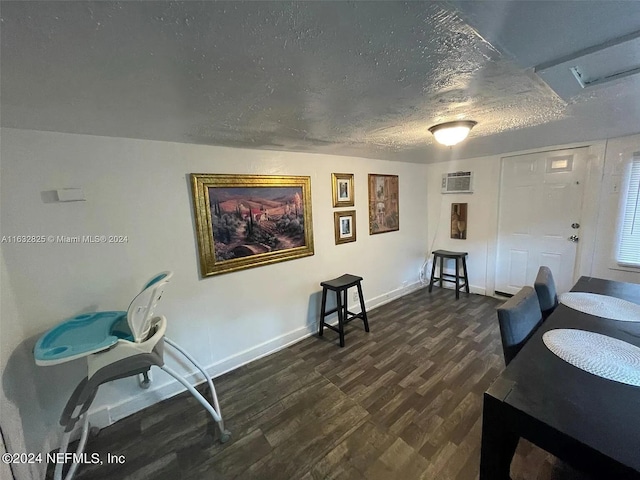 dining room featuring a textured ceiling, an AC wall unit, and dark wood-type flooring