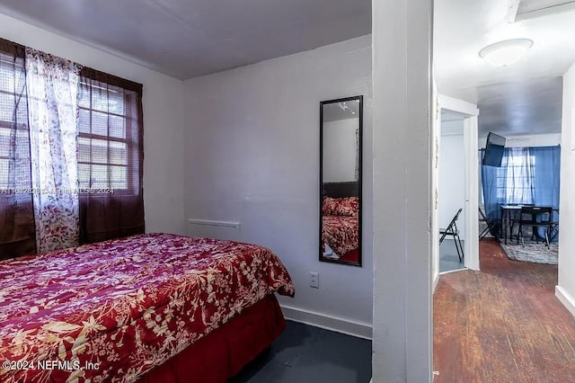 bedroom with multiple windows and dark hardwood / wood-style floors