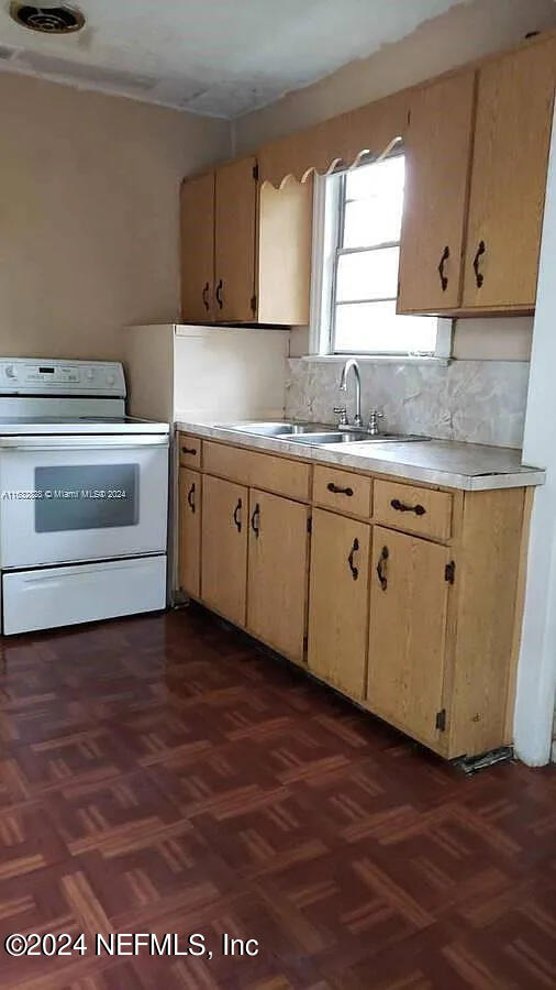 kitchen with light brown cabinets, sink, dark parquet flooring, white range oven, and decorative backsplash