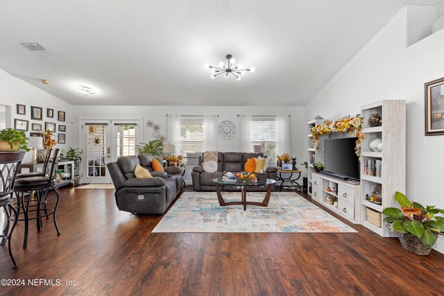 living room with an inviting chandelier, a textured ceiling, dark wood-type flooring, and vaulted ceiling