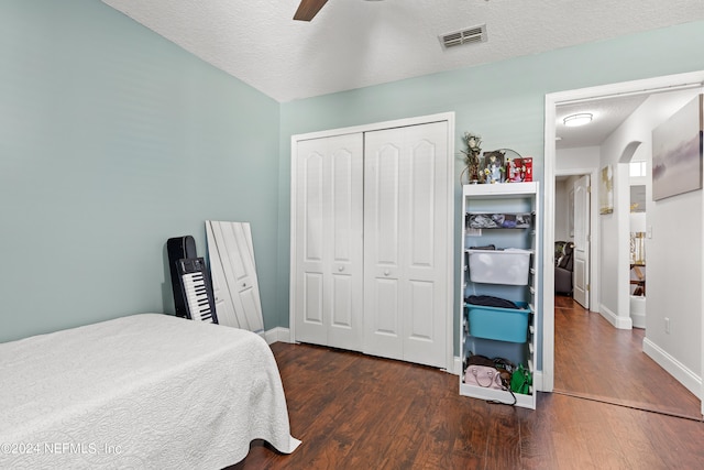 bedroom featuring a textured ceiling, dark hardwood / wood-style flooring, ceiling fan, and a closet