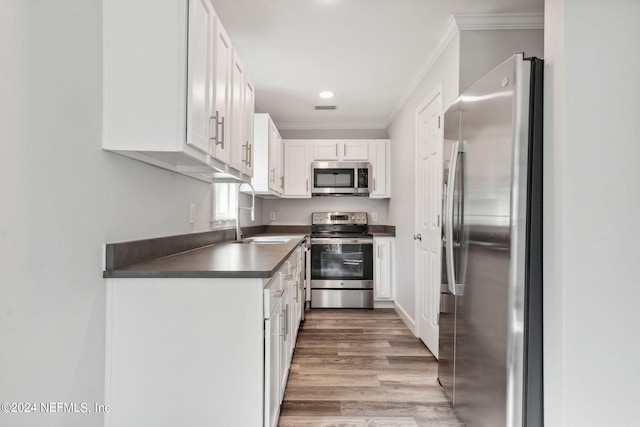 kitchen featuring sink, light hardwood / wood-style flooring, white cabinetry, appliances with stainless steel finishes, and crown molding