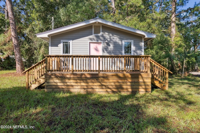 back of property featuring a wooden deck and a lawn