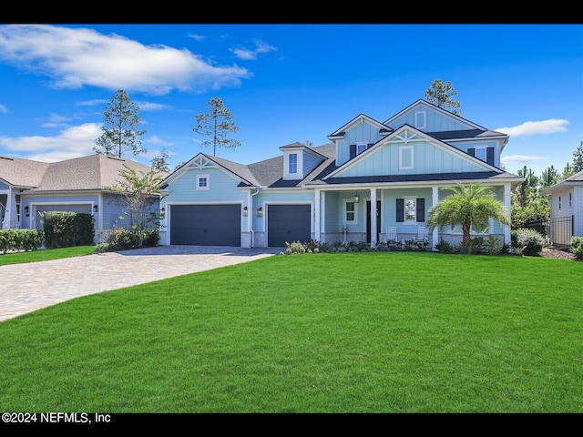 view of front facade featuring a front yard, a garage, and a porch