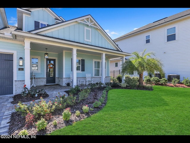 view of front facade with a garage, a front yard, central AC, and covered porch