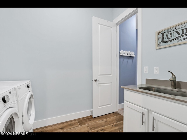 laundry room with cabinets, light wood-type flooring, sink, and washer and dryer