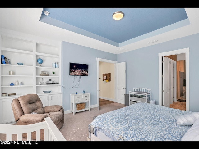 bedroom with a tray ceiling and light carpet