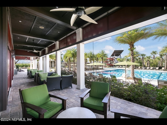 view of patio with an outdoor living space, ceiling fan, and a community pool