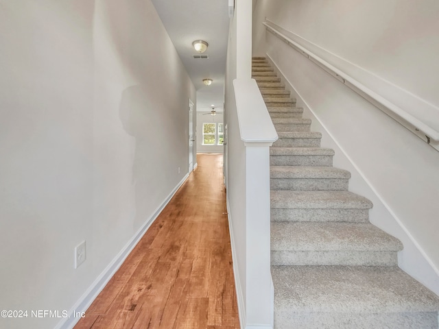 staircase with ceiling fan and hardwood / wood-style flooring