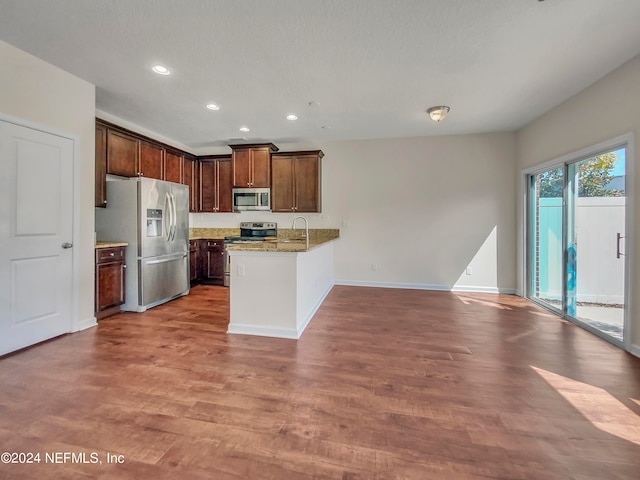 kitchen featuring light stone countertops, appliances with stainless steel finishes, hardwood / wood-style floors, and sink