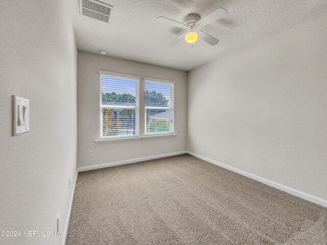 carpeted spare room featuring ceiling fan and a textured ceiling