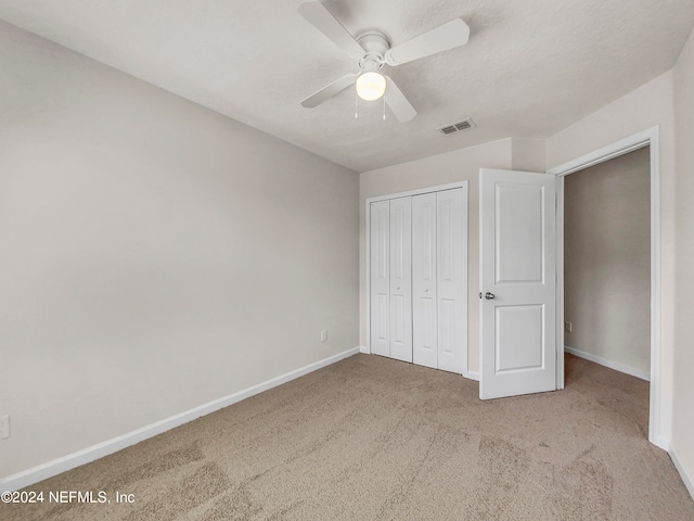 unfurnished bedroom featuring carpet flooring, ceiling fan, and a closet