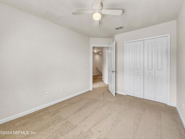 unfurnished bedroom featuring a closet, ceiling fan, and light colored carpet