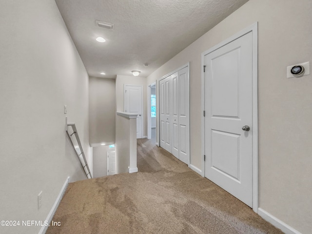 corridor with carpet floors and a textured ceiling