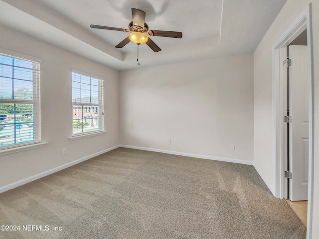 unfurnished room with light carpet, ceiling fan, and a raised ceiling