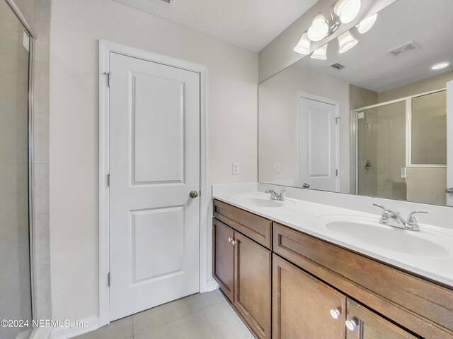 bathroom featuring tile patterned flooring, vanity, and an enclosed shower