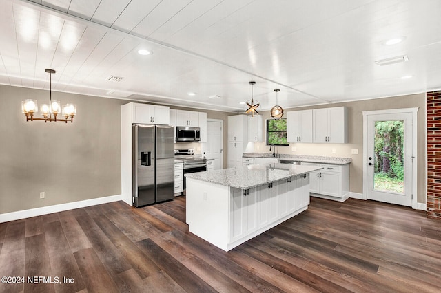 kitchen with white cabinets, a center island, appliances with stainless steel finishes, and decorative light fixtures