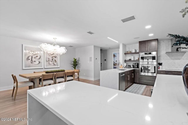 kitchen with dark brown cabinets, light wood-type flooring, sink, decorative backsplash, and stainless steel appliances