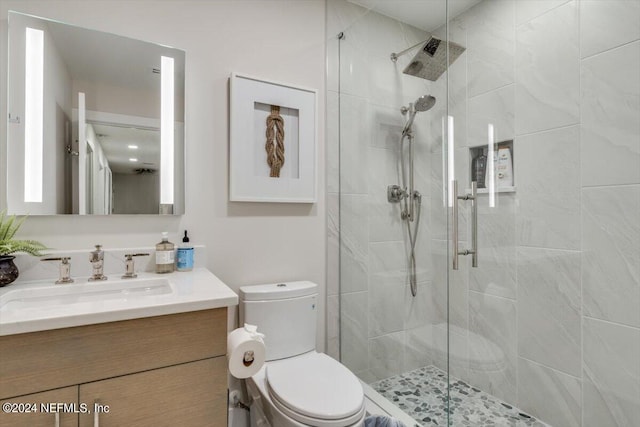 bathroom with a shower with shower door, vanity, and toilet