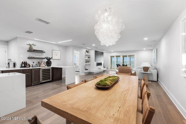 dining area featuring an inviting chandelier, beverage cooler, and light hardwood / wood-style floors