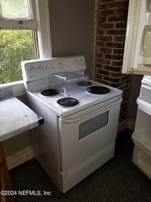 interior space with brick wall and white range with electric cooktop