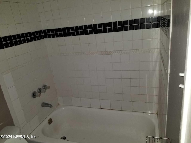 bathroom featuring toilet and tiled shower / bath