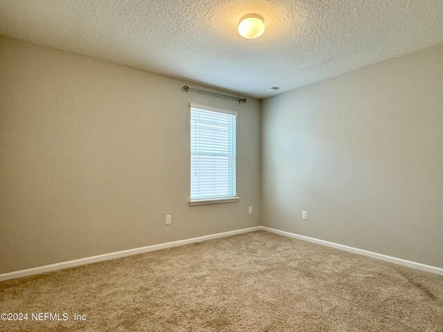 carpeted empty room featuring a textured ceiling