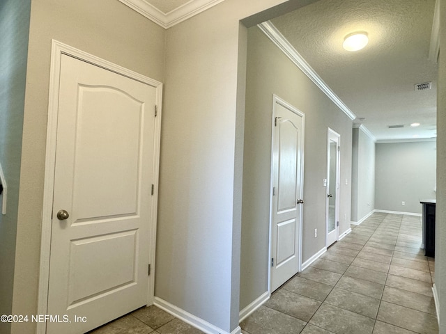 hallway featuring a textured ceiling, light tile patterned floors, and crown molding