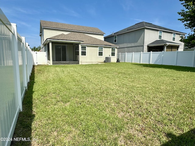 rear view of property featuring central air condition unit, a sunroom, and a yard