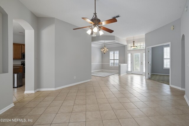 tiled empty room with ceiling fan with notable chandelier