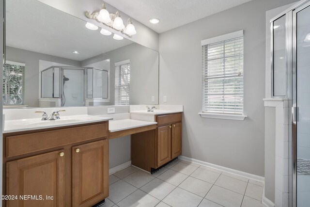 bathroom featuring vanity, a shower with shower door, tile patterned flooring, and a textured ceiling