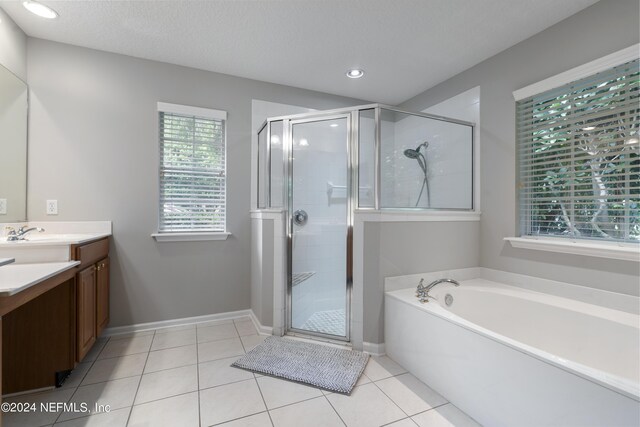 bathroom featuring shower with separate bathtub, vanity, tile patterned floors, and a wealth of natural light