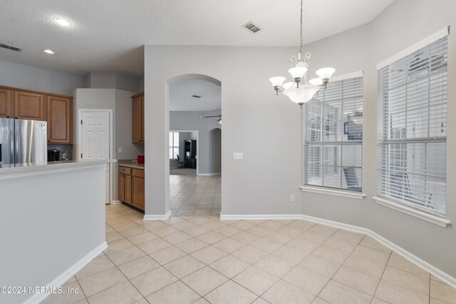 kitchen with stainless steel fridge, decorative light fixtures, an inviting chandelier, and plenty of natural light