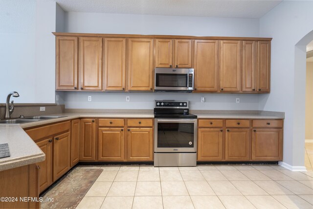 kitchen featuring appliances with stainless steel finishes, light tile patterned flooring, and sink