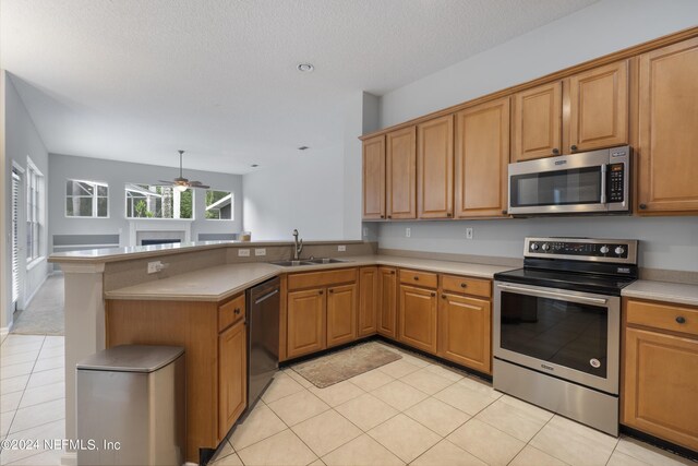 kitchen featuring sink, kitchen peninsula, stainless steel appliances, light tile patterned floors, and ceiling fan