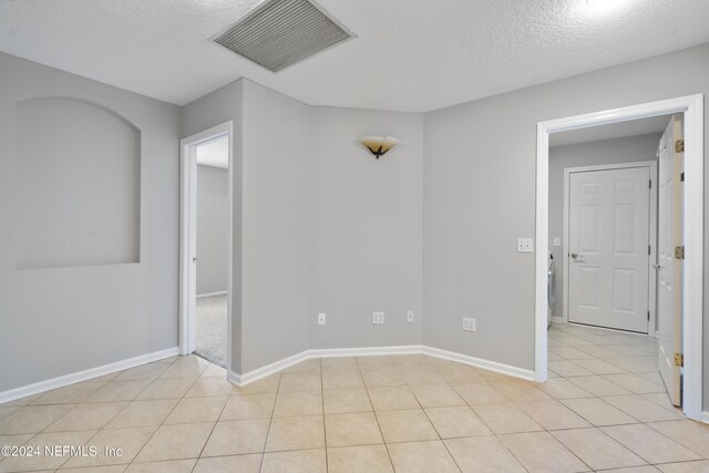 empty room featuring a textured ceiling and light tile patterned floors