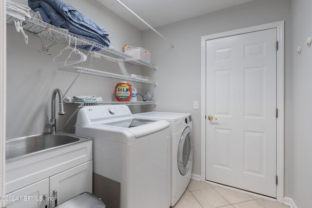 washroom with cabinets, independent washer and dryer, light tile patterned floors, and sink