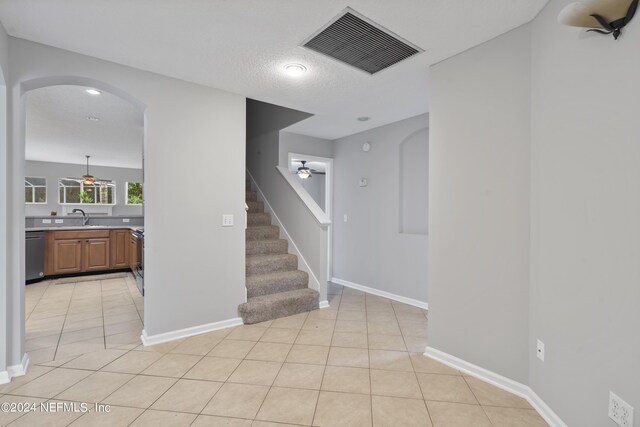 stairway featuring a textured ceiling, ceiling fan, tile patterned floors, and sink