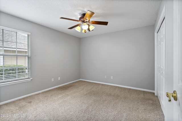 interior space featuring a textured ceiling, carpet, ceiling fan, and a closet